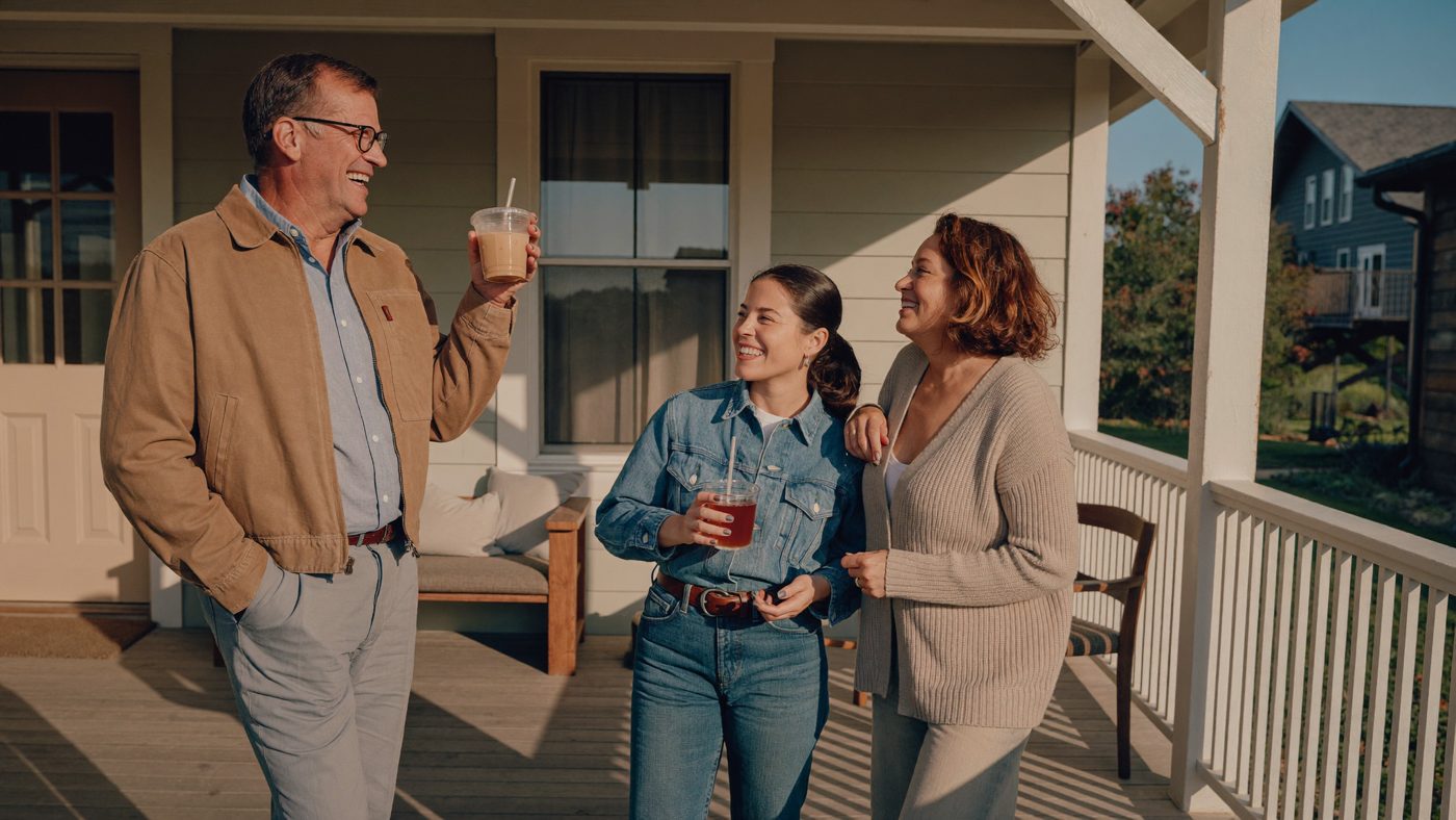 Illustrative: three adults laughing on a farmhouse porch